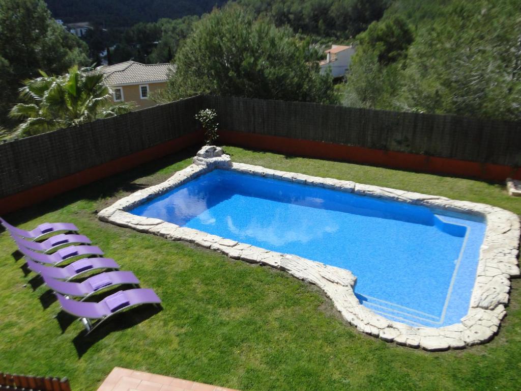 una piscina con 2 tumbonas y un patio con una valla en Villa Olivo Cerra da, en Canyelles