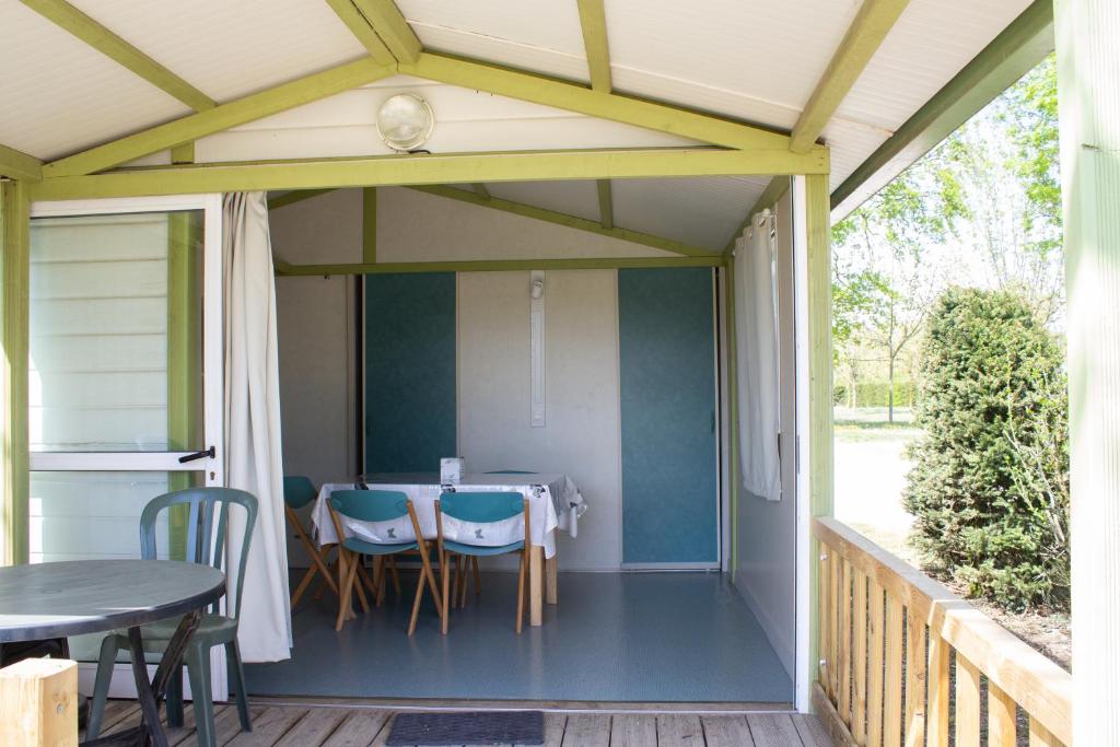 - une terrasse couverte avec une table et des chaises dans l'établissement Camping Les Charmilles, à Vallières