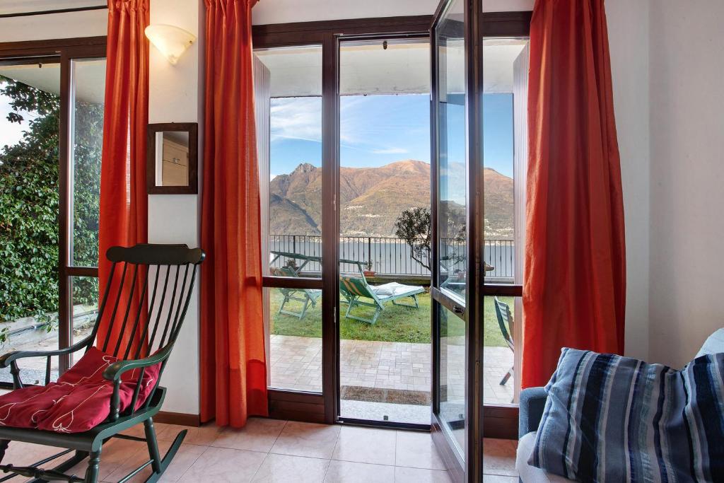 a room with a chair and a view of the mountains at Ampia vista sul lago di Como in Bellano