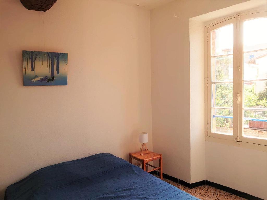 a bedroom with a blue bed and a window at 5COMA2 Appartement proche plage in Collioure