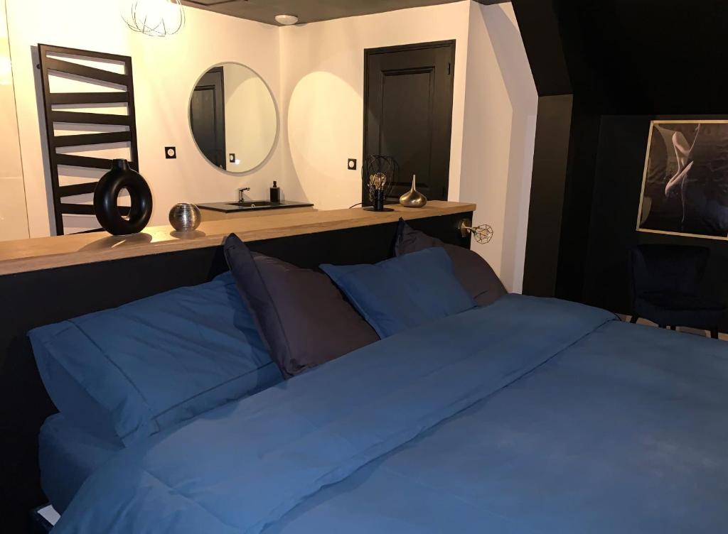 una camera con letto blu e specchio di L'Eclipse maison romantique avec Jacuzzi 