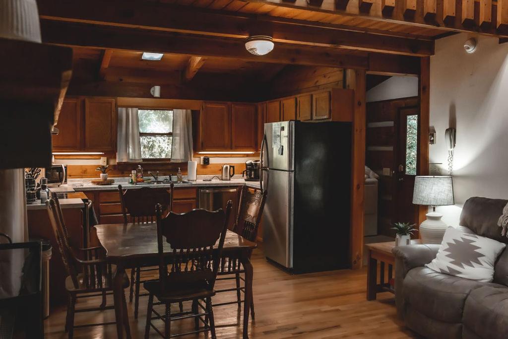 eine Küche und ein Wohnzimmer mit einem Tisch und einem Kühlschrank in der Unterkunft Creekside Overlook at 36 North Cabin - Fireplace in Purlear