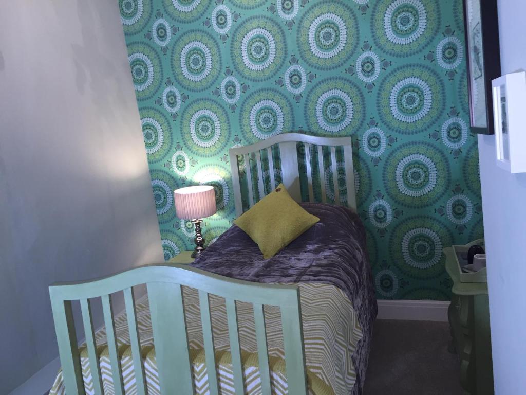 a crib in a room with a green and blue wallpaper at Old Croft House in Kirkby Stephen