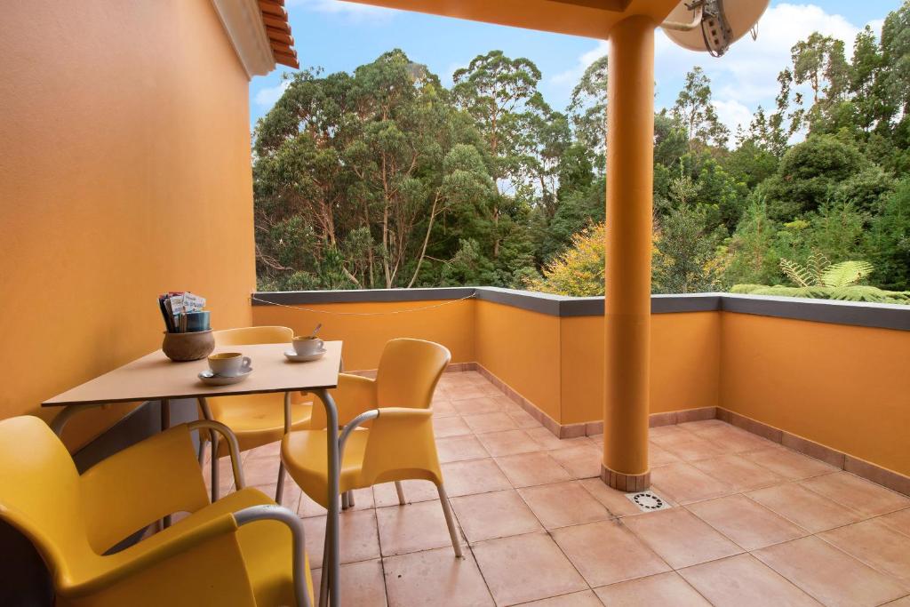 ein Balkon mit Tisch und Stühlen und einem großen Fenster in der Unterkunft Casa Catarina in Junqueira