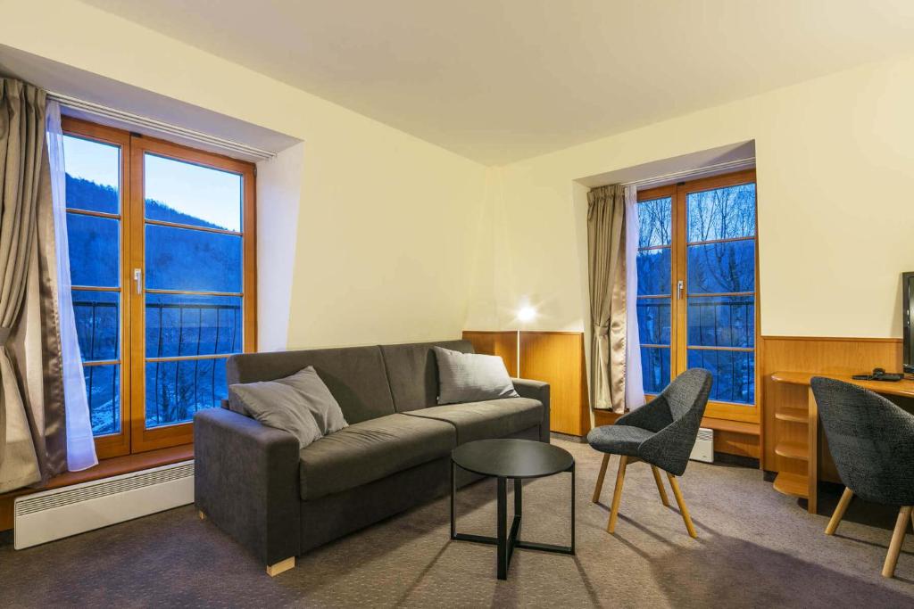 a living room with a couch and chairs and windows at Hotel Ostrov in Tisá