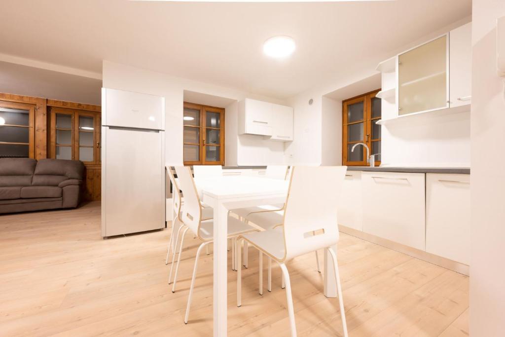 eine weiße Küche mit einem weißen Tisch und Stühlen in der Unterkunft Cesa Meida 2A in Pozza di Fassa