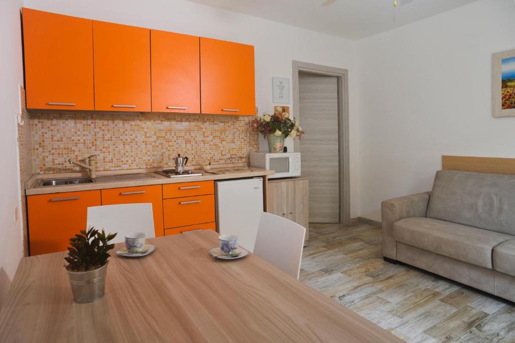 une cuisine avec des armoires orange, une table et un canapé dans l'établissement La Casa dei Nonni sul Garda, à Peschiera del Garda