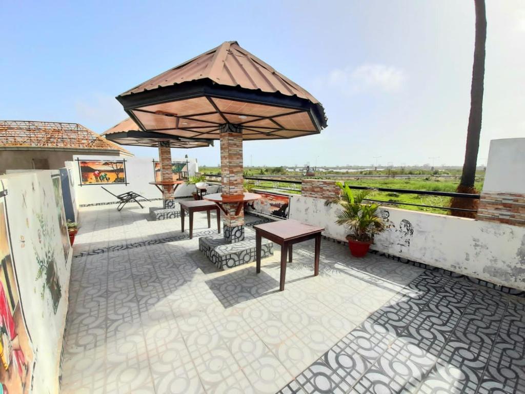 eine Außenterrasse mit Tischen und einem Sonnenschirm in der Unterkunft Gloton apartments in Sere Kunda