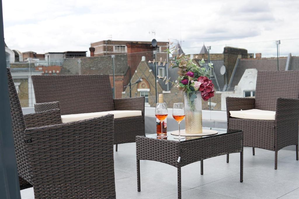 homely - Central London Camden Penthouse Apartment في لندن: طاولة مع كأسين من النبيذ و مزهرية مع الزهور