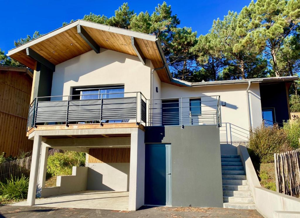 une maison avec un balcon et des escaliers dans l'établissement Villa Palot à la plage, à Mimizan