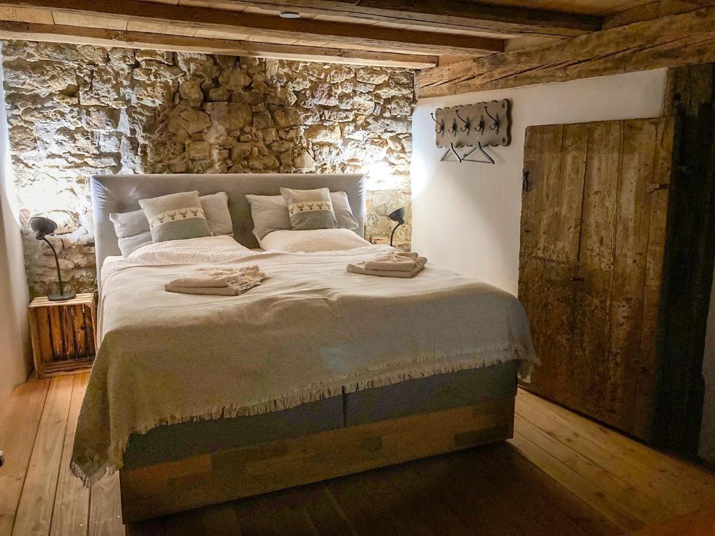 een slaapkamer met een groot bed en een stenen muur bij PEARLs - Stilvolle Wohnung zwischen dem Schwarzwald & der Schweiz in Stühlingen