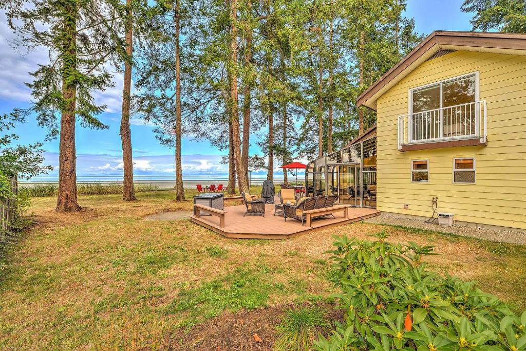 een achtertuin met een terras met banken en bomen bij Kye Bay Winter Beach House in Comox