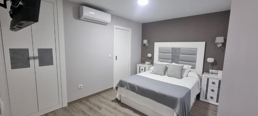 um quarto branco com uma cama e um espelho em Virrey del Pino - Apartamento en Baena em Baena