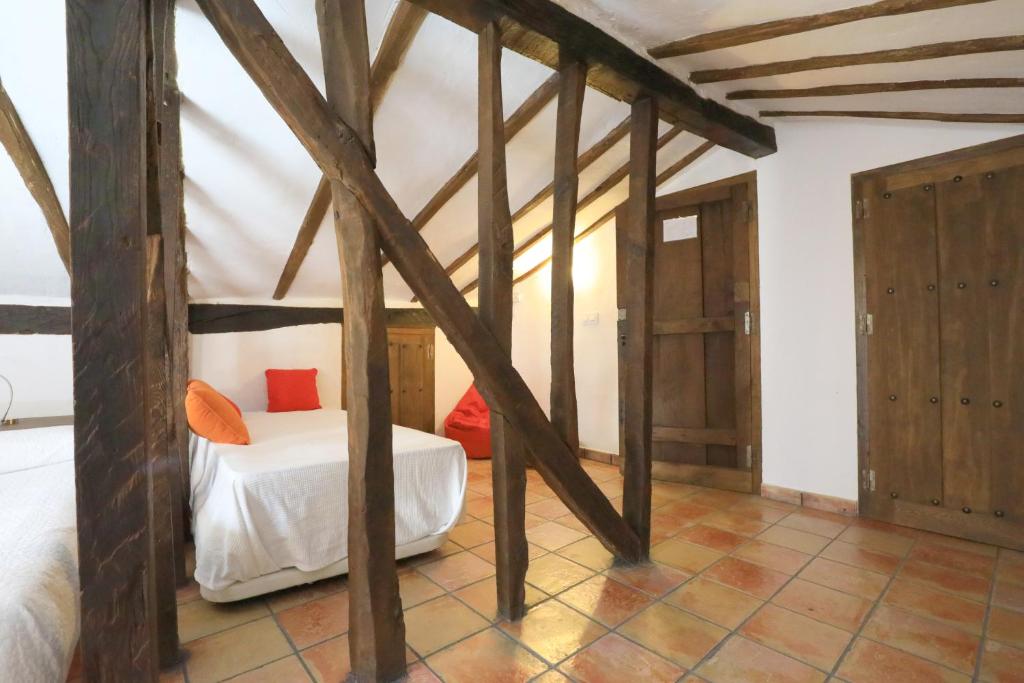 a bedroom with a bed in a room with wooden beams at Apartamentos Rurales SPA Casa De Los Escudos in Valverde de la Vera