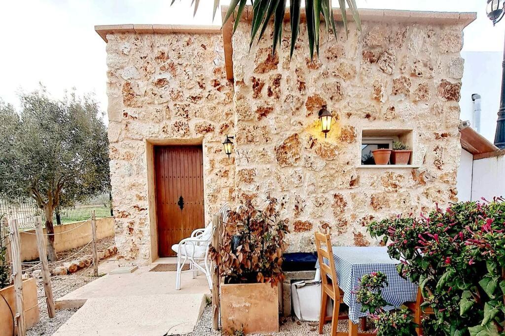 a stone building with a table and chairs in front of it at La Gardana, casa de campo mallorquina in Porreres