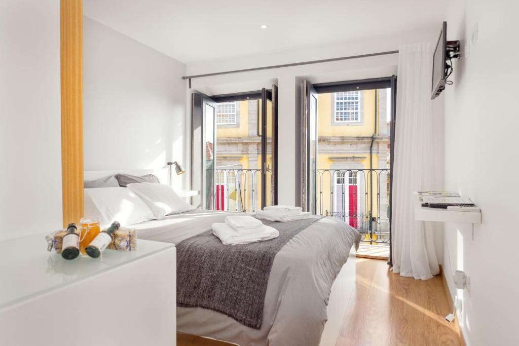 a white bedroom with a bed and a large window at Be In Oporto in Porto