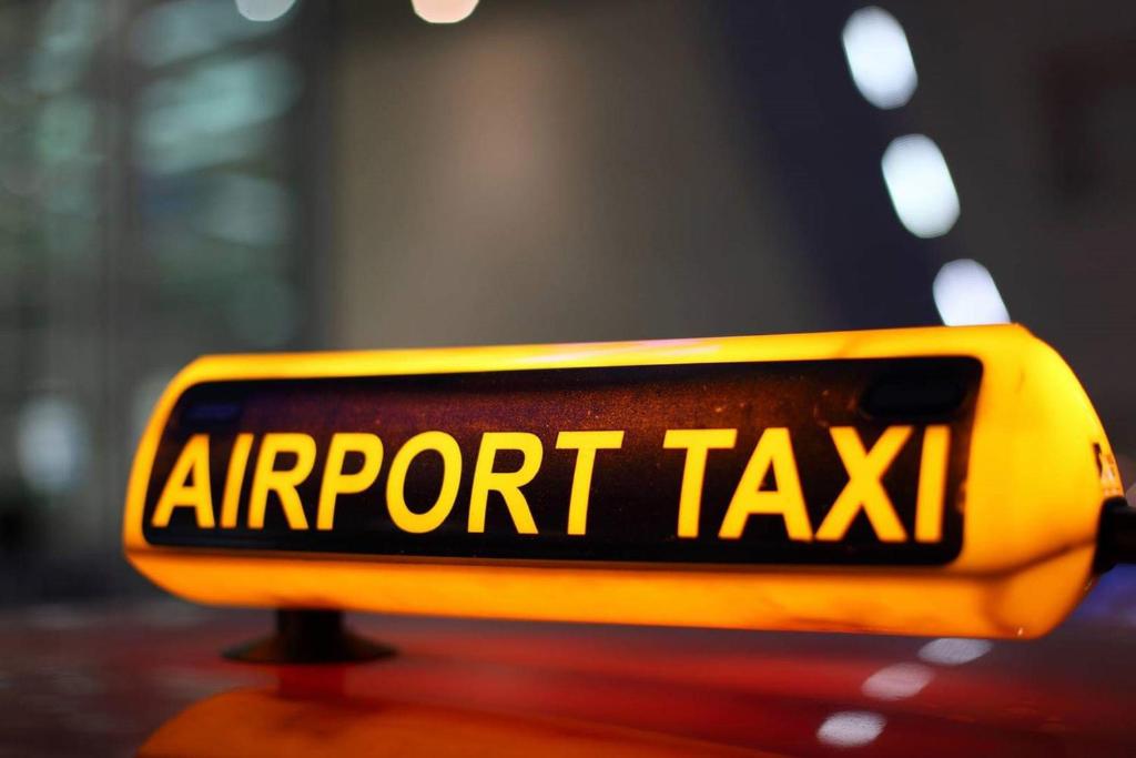 AIRPORT HOTEL Entebbe في عنتيبي: لافته تقول تاكسي المطار جالس فوق سياره
