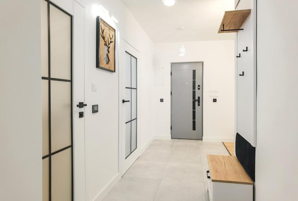 korytarz z białymi ścianami i drzwiami oraz drewnianym stołem w obiekcie Apartament Green Forest w mieście Duszniki Zdrój