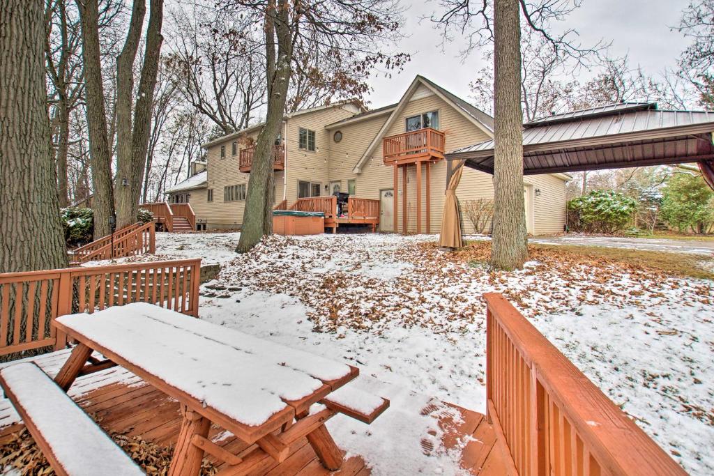 a house with a snow covered yard with a wooden bench at Ortonville Retreat with 2 Decks and Lake Access! in Ortonville