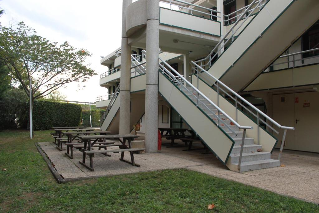 a group of picnic tables next to a building with a staircase at Hôtel Premiere Classe Pamiers in Pamiers