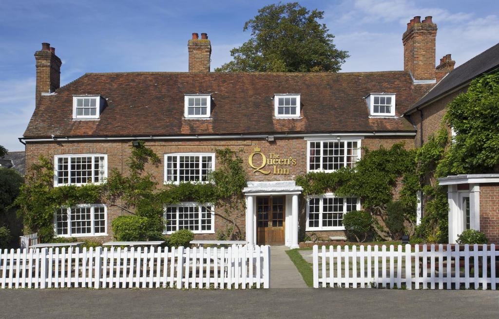 una cerca blanca frente a un edificio en The Queen's Inn en Hawkhurst