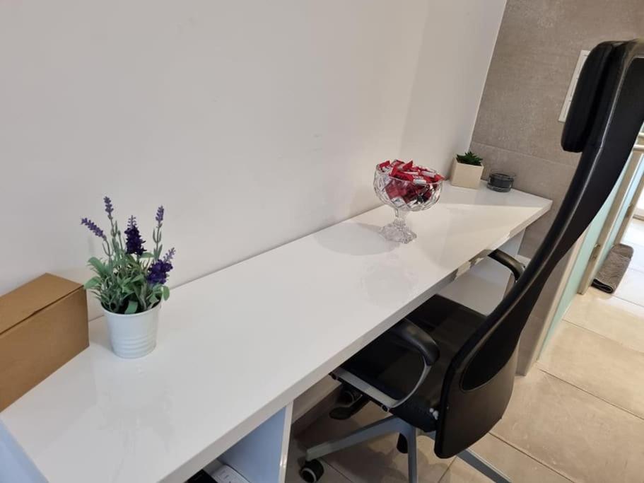 einen weißen Schreibtisch mit einer Vase und Blumen darauf in der Unterkunft Modern studio apartment A in Athen