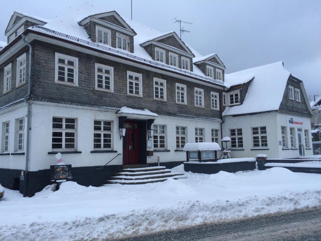 a large white building with a red door in the snow at Der Engel in Winterberg