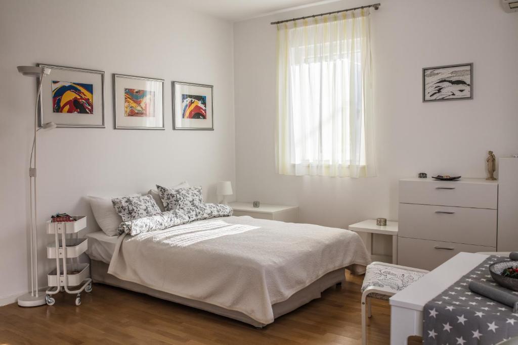 een witte slaapkamer met een bed en een dressoir bij Apartman BeBe in Zagreb