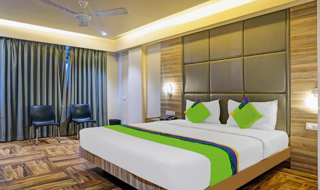 1 dormitorio con 1 cama grande y 2 sillas en Treebo Trend Classic Grande, Camp en Pune