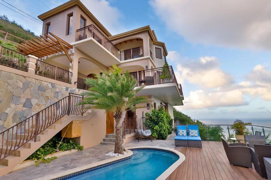 a house with a swimming pool and a balcony at Modern 3-bedroom villa with pool in Tortola Island
