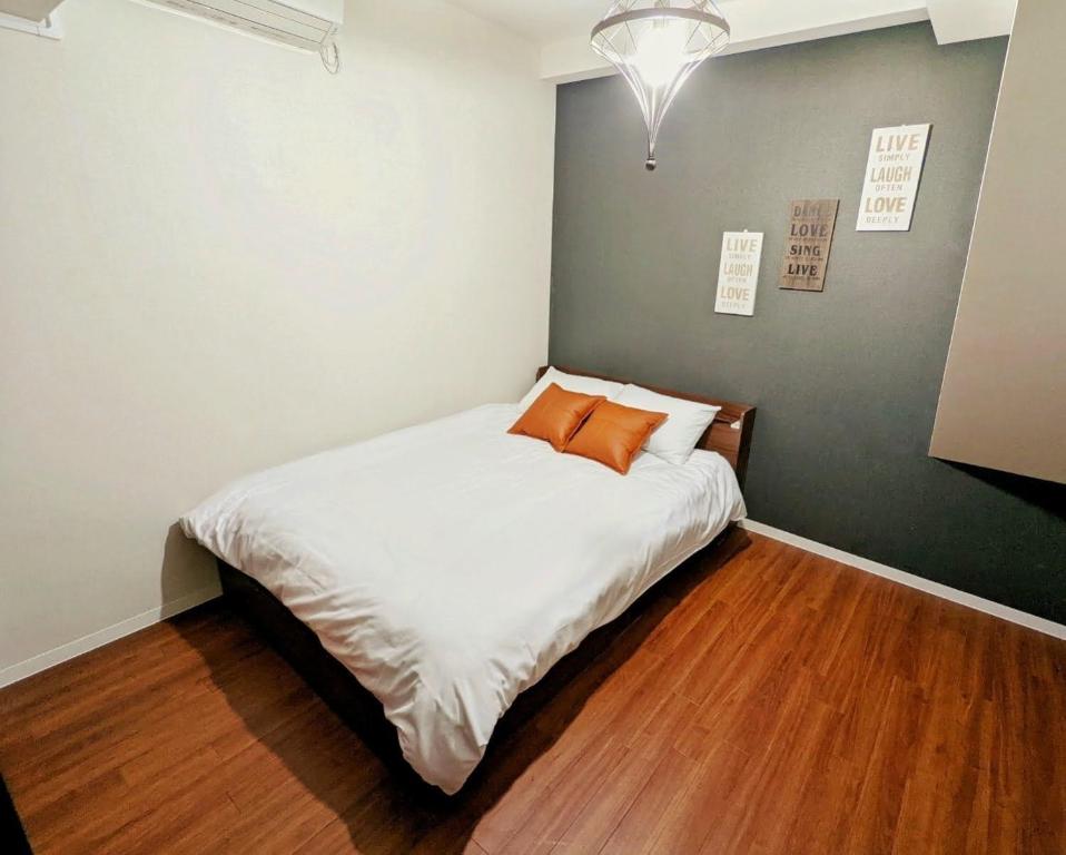 a bedroom with a bed with white sheets and orange pillows at Amber Iidabashi - Vacation STAY 87112v in Tokyo