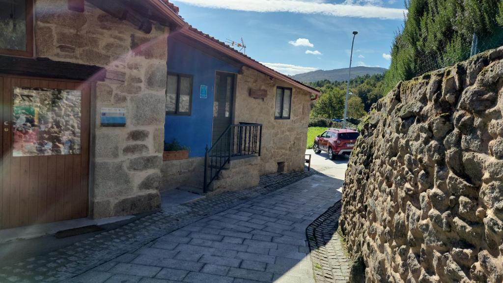 a building with a stone wall next to a street at Casa Cerralleiro. Casa vacacional en Parada de Sil. Ribeira Sacra. in Parada del Sil