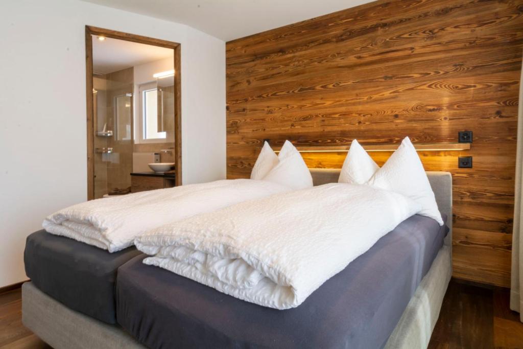 ein Schlafzimmer mit einem großen Bett und einer Holzwand in der Unterkunft Chalet Weisshorn 1 in Bettmeralp