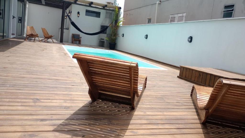 a swimming pool with two chairs and a pool at The Guest House hostel in Balneário Gaivotas