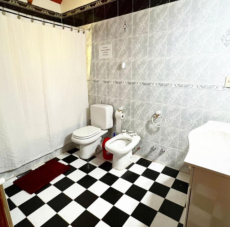 a bathroom with a toilet and a checkered floor at Ruca Quimei Malek in San Carlos de Bariloche