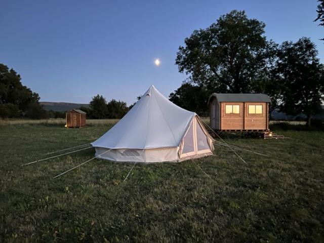 a white tent in a field next to a cabin at Gwynfyd Bell Tent in Abergavenny