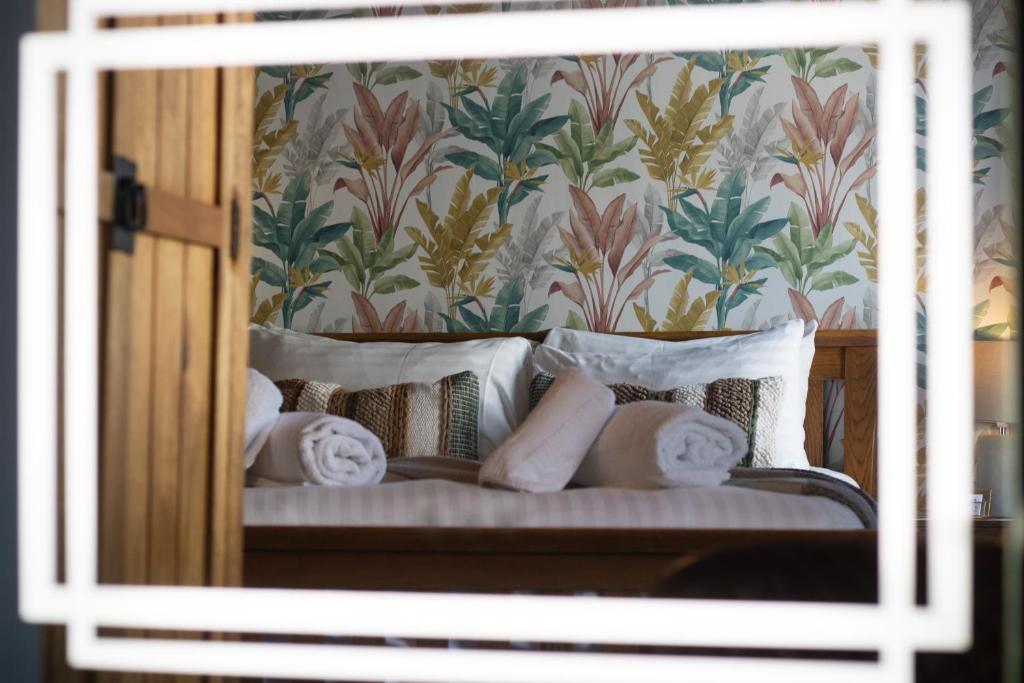 uma cama com almofadas brancas e um papel de parede floral em The Wheatsheaf Pub, Kitchen & Rooms em Bingham