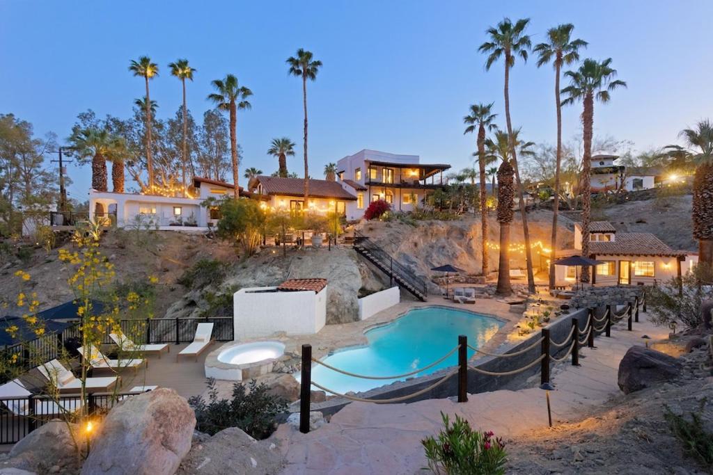 a resort with a swimming pool and palm trees at Television Host and Designer Bobby Berk Invites You To His Desert Oasis in Palm Desert