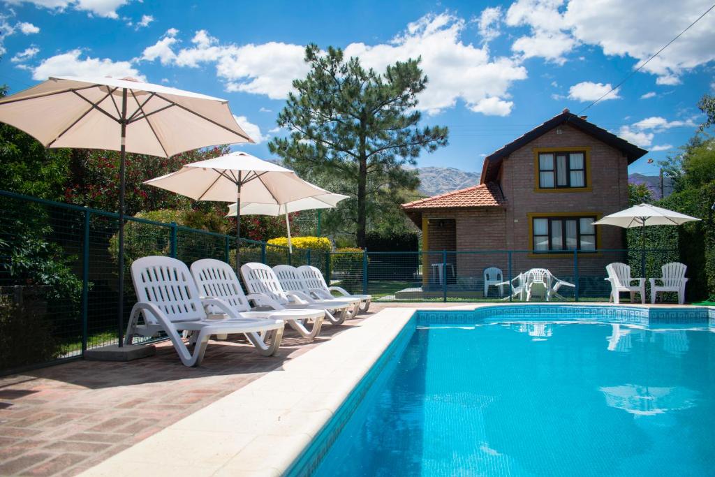 uma piscina com cadeiras e guarda-sóis e uma casa em Cabañas Monteolivos em Merlo