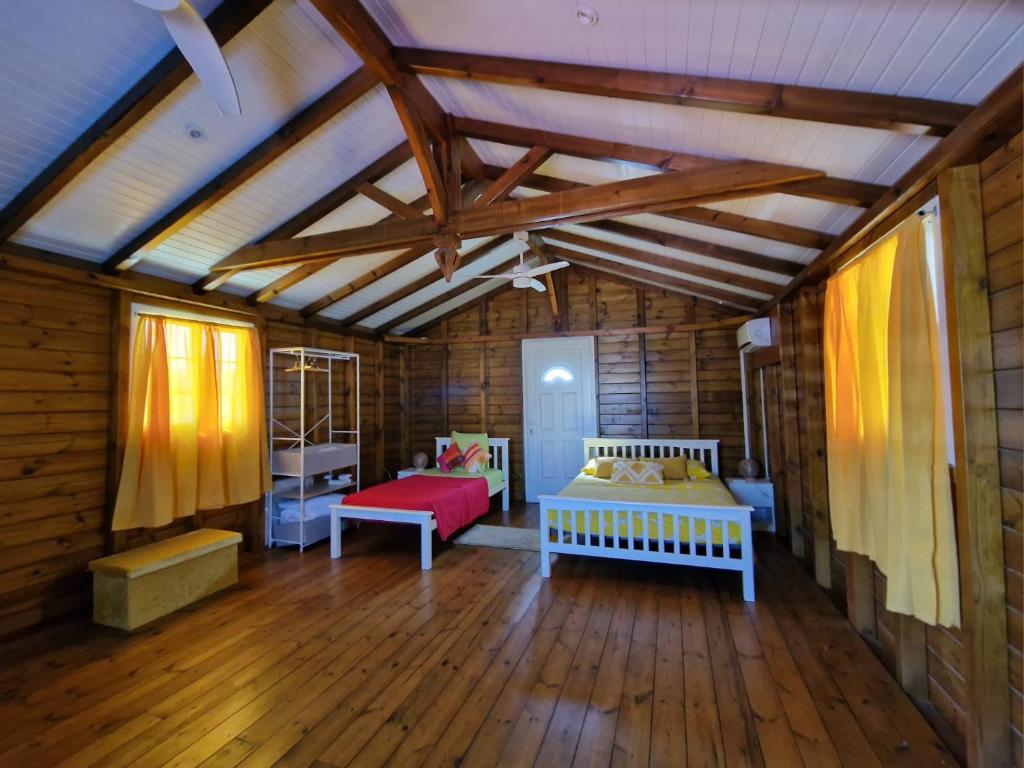 a bedroom with two beds in a wooden room at Le Cosy Bungalow de Lili / 5min de l'aéroport in Les Abymes