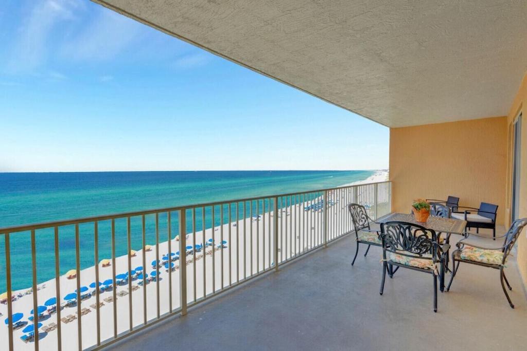 a balcony with a table and chairs and the beach at Treasure Island 707 - Gulf front, sunset views, heated resort pool & hot tub! in Panama City Beach