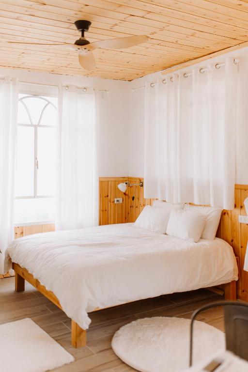 una camera da letto con un letto grande con tende bianche di Tobiana Desert Lodging Negev a ‘Ezuz