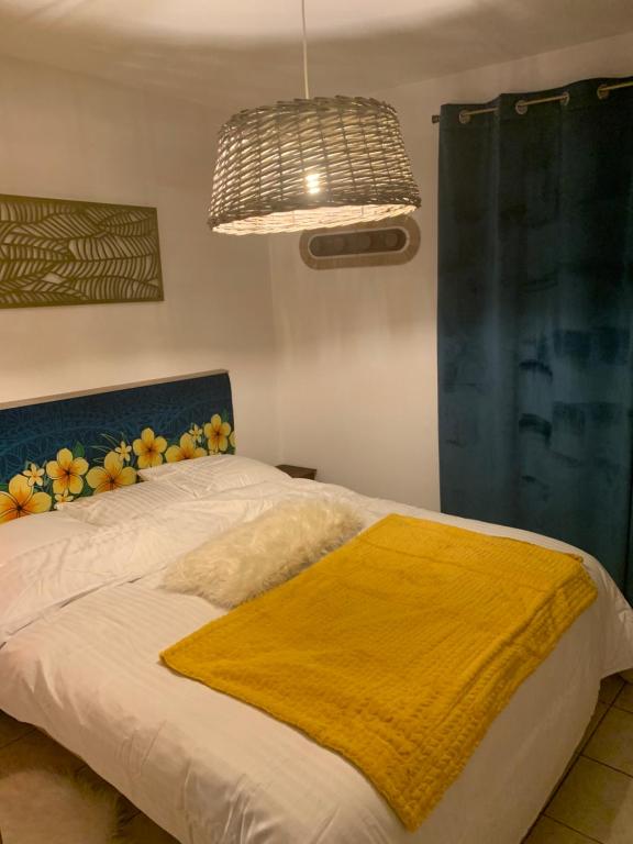 Un dormitorio con una cama con una manta amarilla. en Le camélia, en Tallard