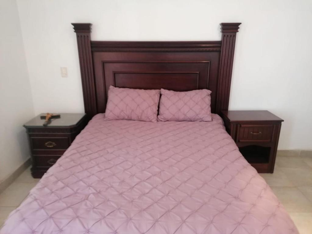 a bed with a pink comforter and two night stands at CASA BERTHA 