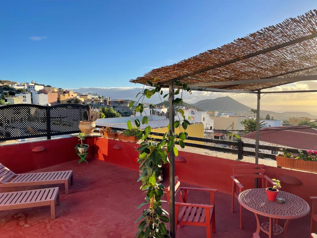 un patio en la azotea con mesas, sillas y una pérgola en Sansofi Guesthouse en San Miguel de Abona