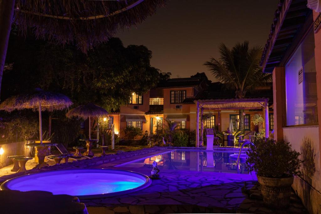 una piscina por la noche con luces moradas en Pousada Estrela da Manhã, en São Pedro da Serra