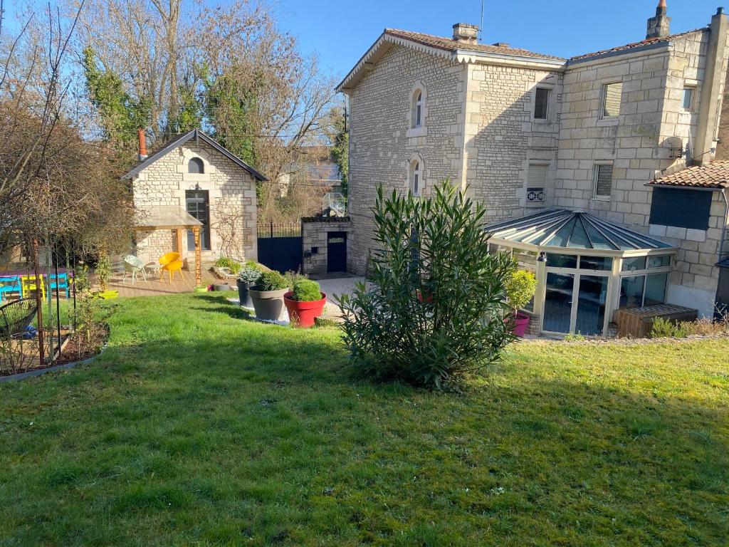 um quintal com uma grande casa de pedra com um jardim em Propriété en bord de Sèvre em Niort