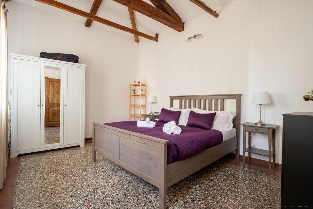 1 dormitorio con 1 cama con sábanas moradas y almohadas blancas en Ca' Giorgia Balcony House, en Venecia