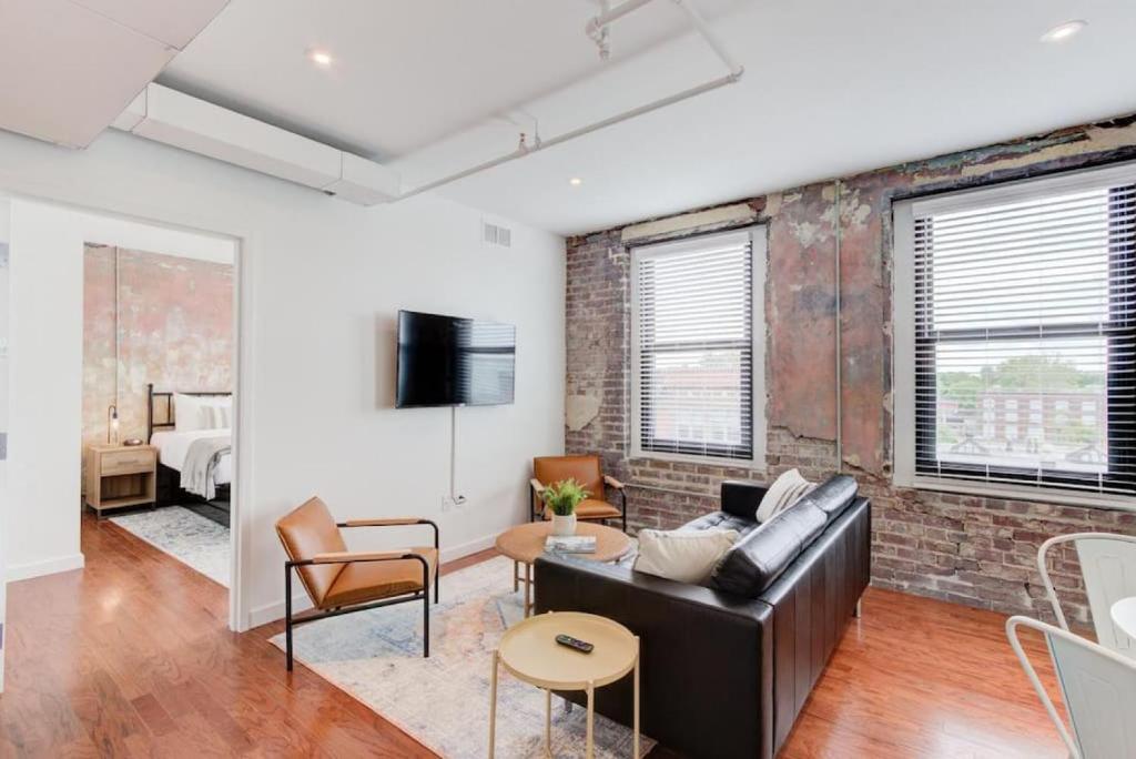 a living room with a leather couch and a brick wall at Right on Main St with Historic Vibe! in Memphis