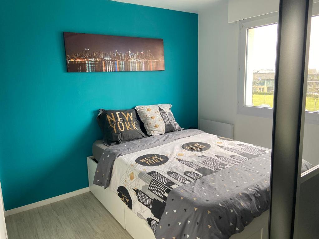 1 dormitorio con 1 cama con pared azul en Grand Studio Lumineux Caen Memorial, en Caen